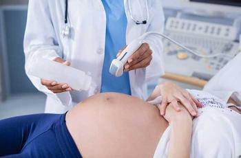 Une sage femme applique le gel sur le ventre d'une femme enceinte et s'apprête à faire une échographie.
